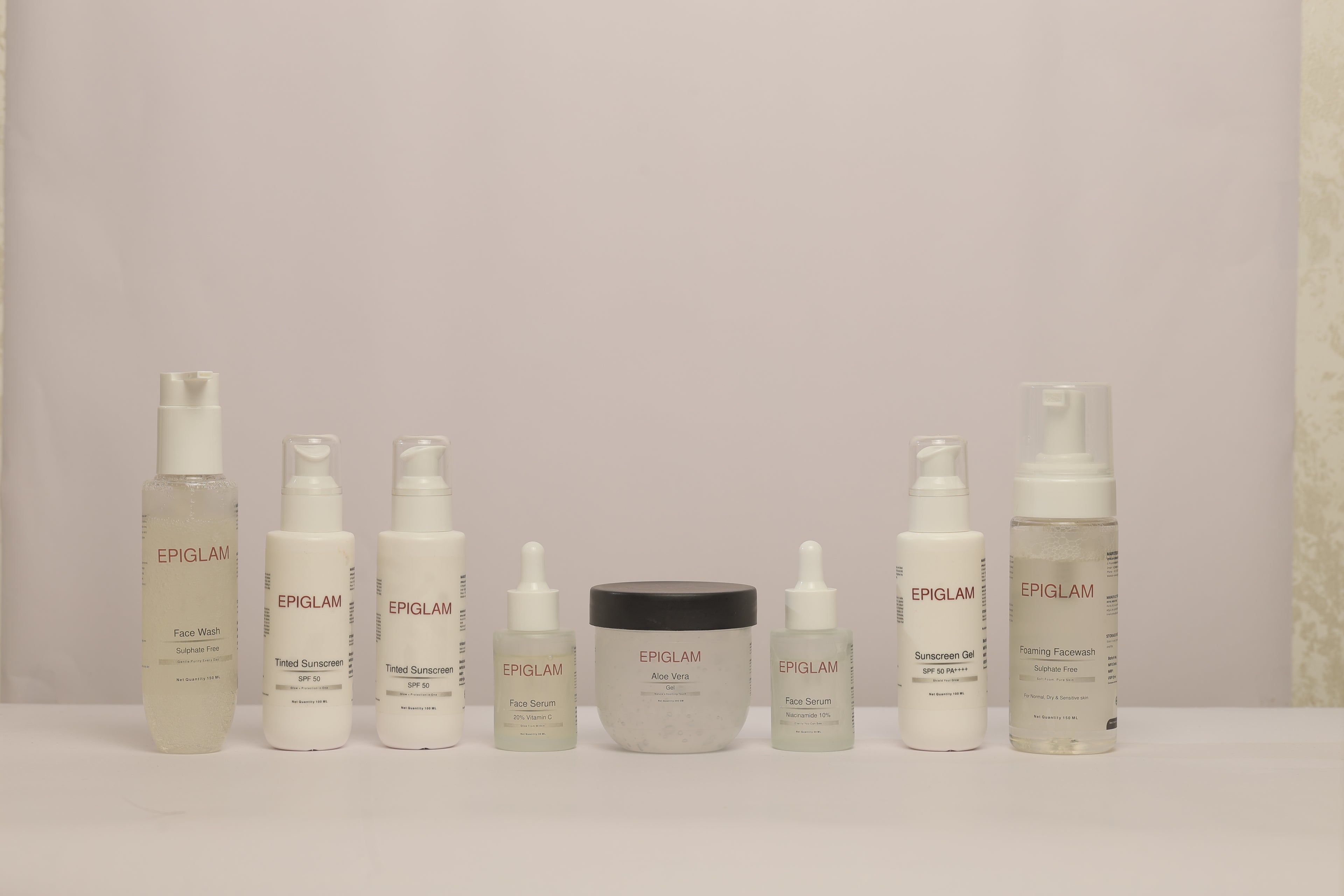 A lineup of Epiglam skincare products—including face wash, sunscreen gel, face serums, aloe vera gel, and tinted sunscreen—neatly arranged in a row against a neutral background, highlighting the variety of the product line.